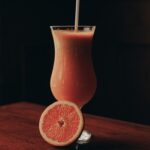 orange juice in clear drinking glass with straw