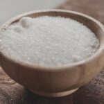 a wooden bowl filled with sugar on top of a wooden table