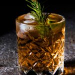 clear drinking glass with yellow liquid and green leaves